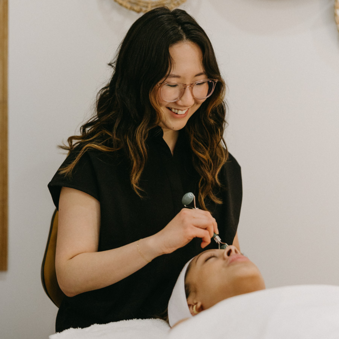 A Skin Revival Specialist is jade rolling a client's face to promote relaxation and blood circulation