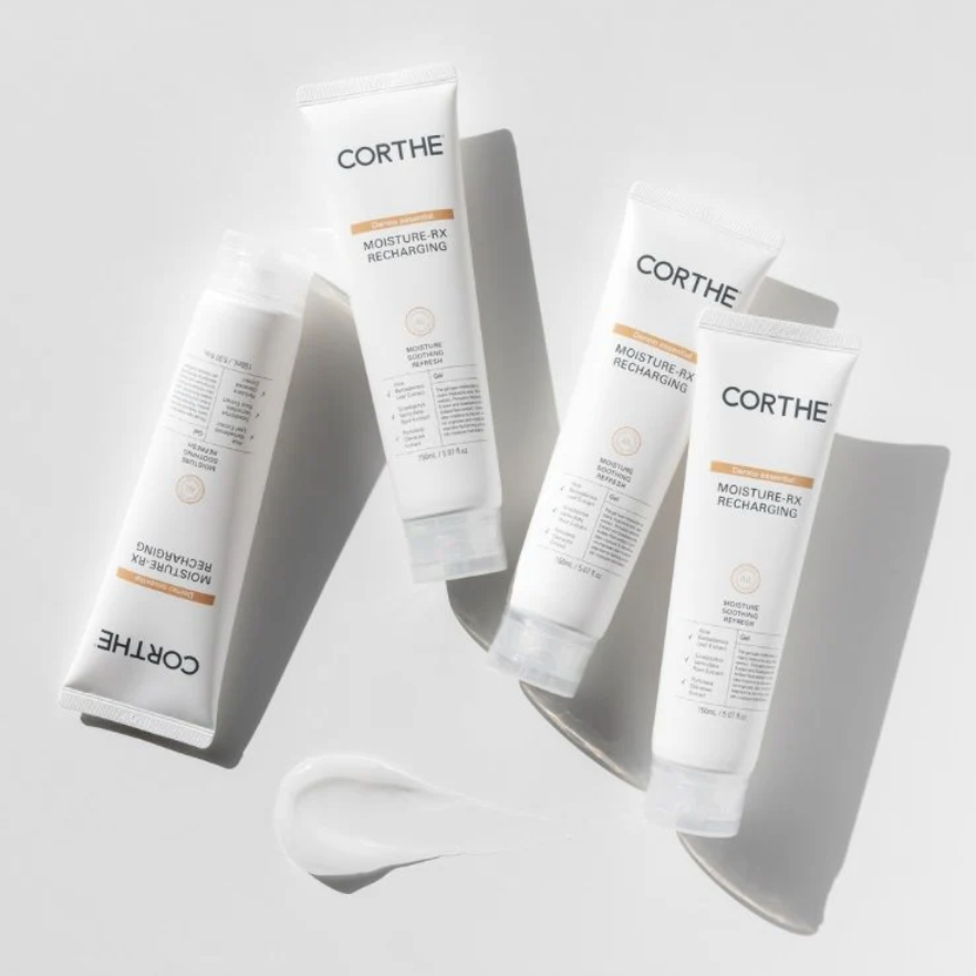 Four tubes of Corthe Dermo Essential Moisture RX Recharging Cream, lined up on a white surface with a reflective background. The packaging is predominantly white with minimalist design and text.